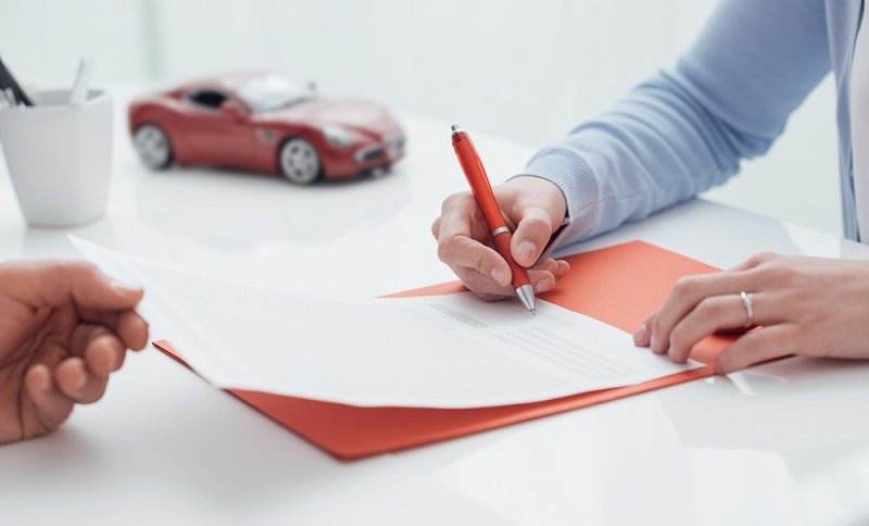 Woman,Signing,A,Car,Insurance,Policy,,The,Agent,Is,Holding